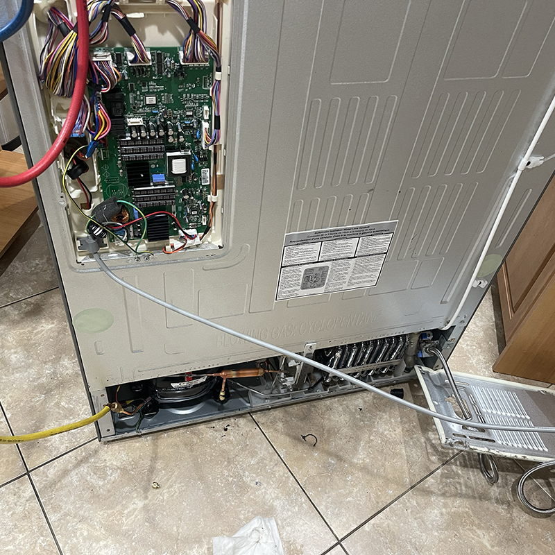 Refrigerator with exposed internal components and circuit board, highlighting appliance repair for Broward County services.