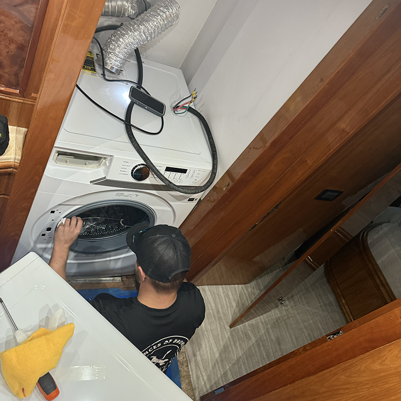 Samsung washer and dryer installation on a motor yacht, technician servicing appliance in tight space, Coral Ridge Yacht Club.